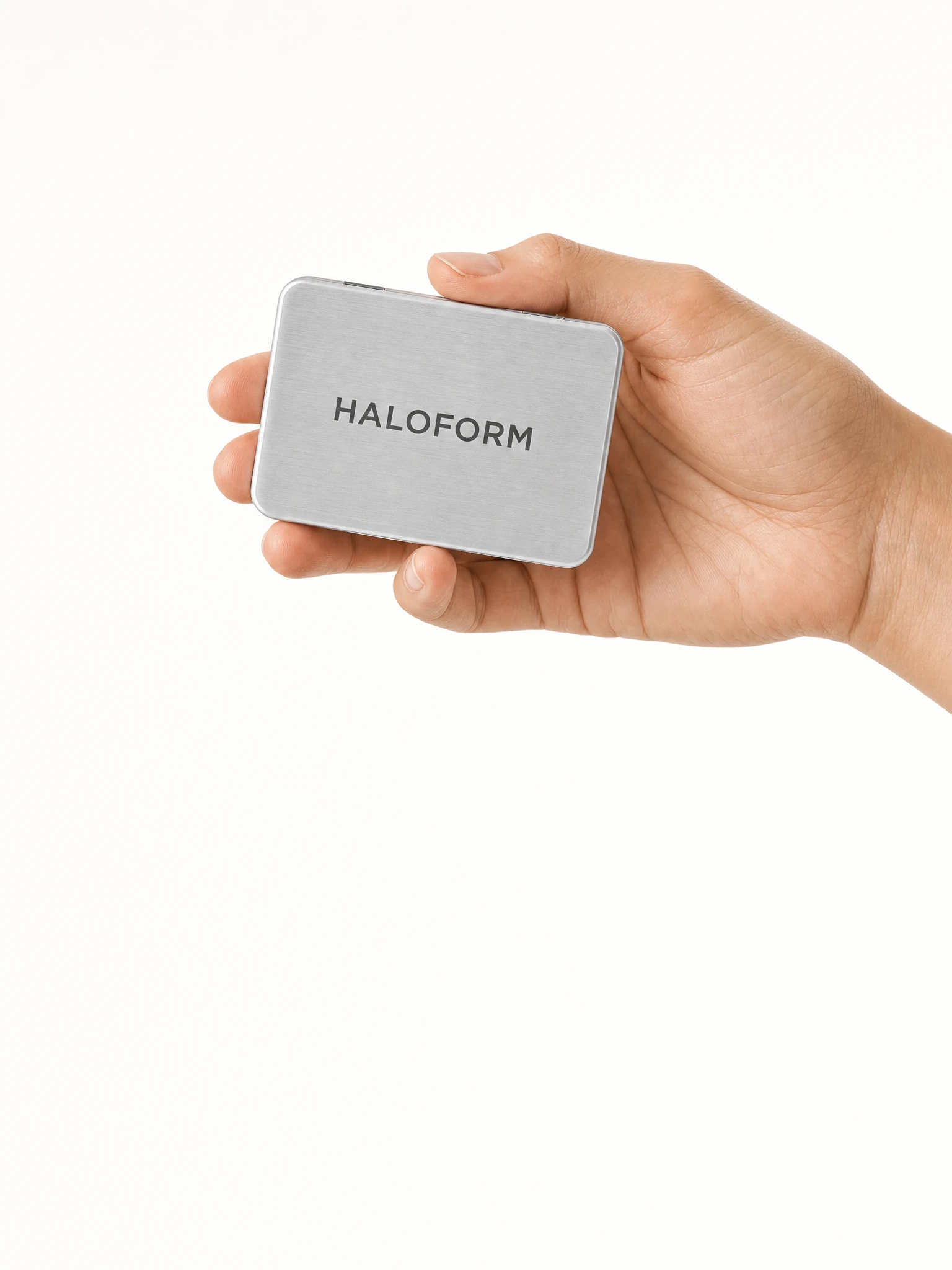 Hand holding a brushed aluminium HALOFORM whitening-film case