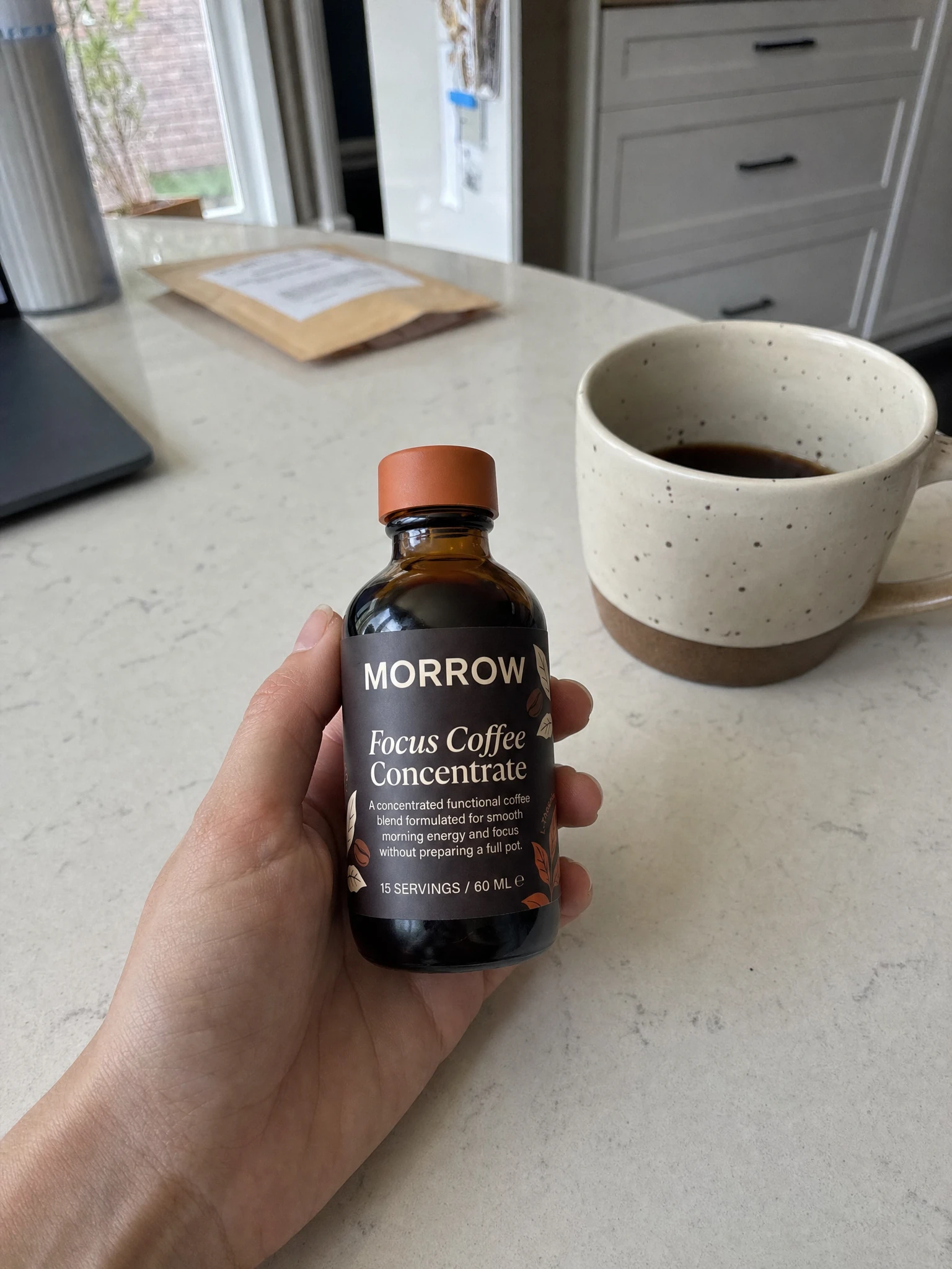 Hand holding MORROW Focus Coffee Concentrate over a morning desk