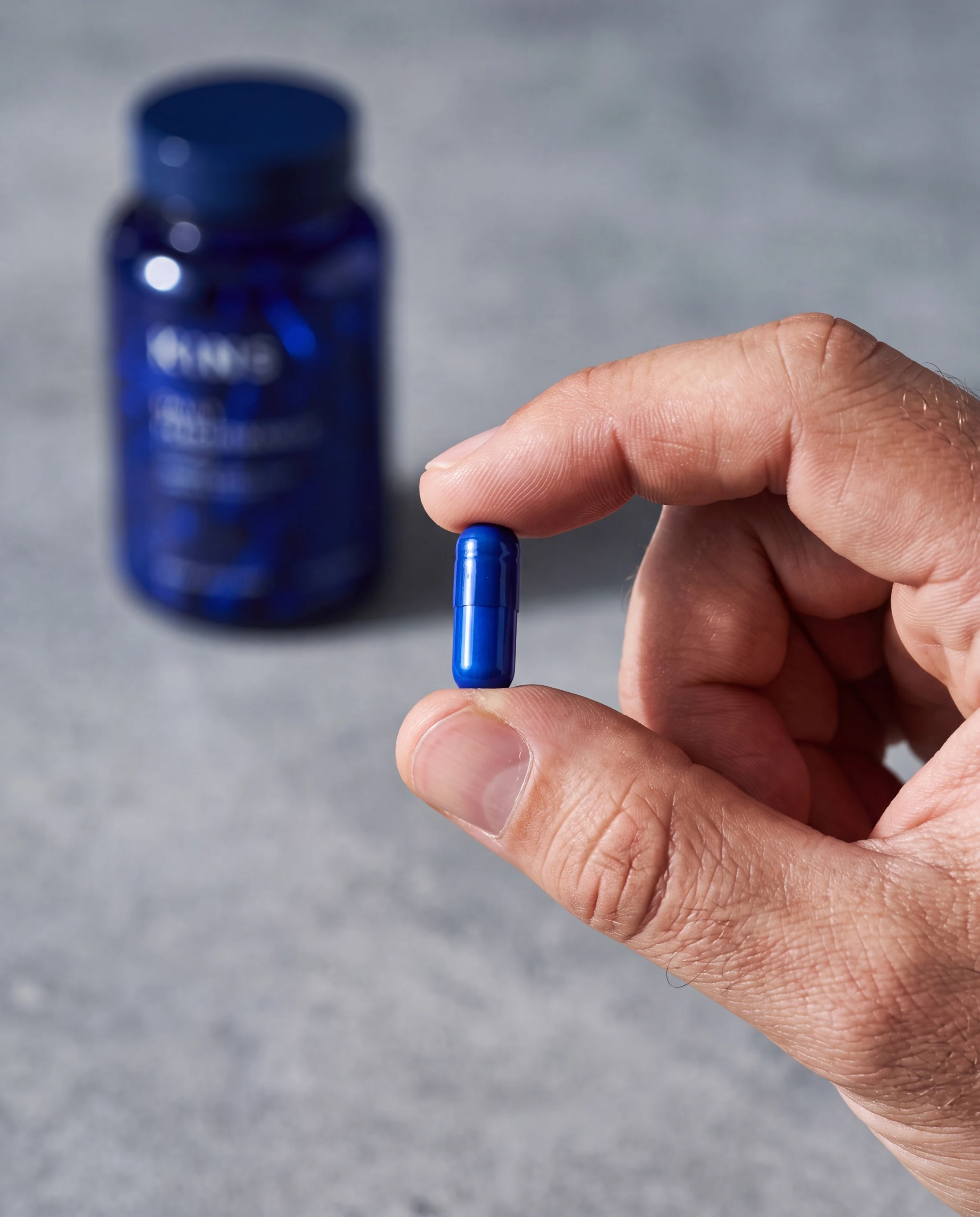 Macro detail of one cobalt capsule held between natural fingers