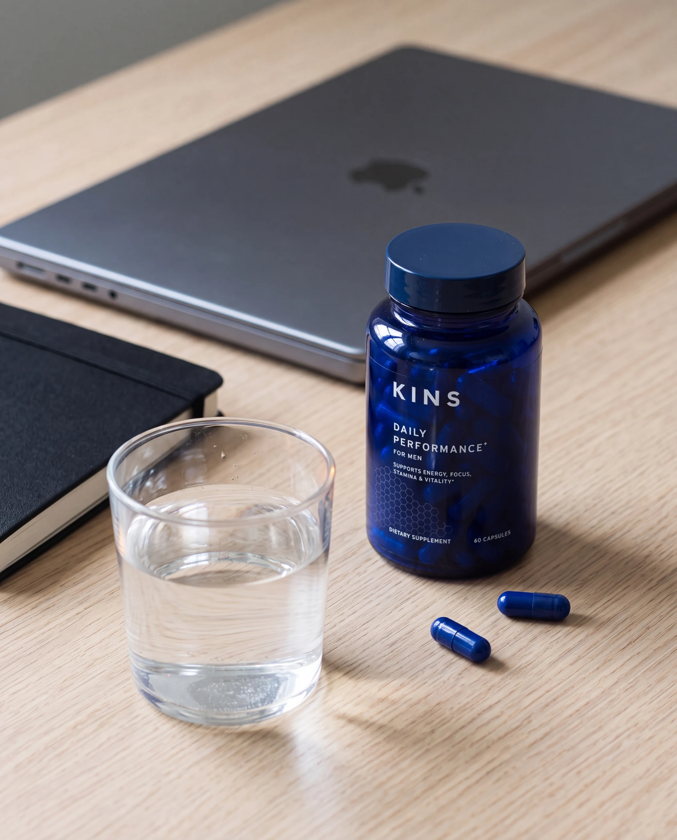 KINS men's supplement beside water and daily desk essentials