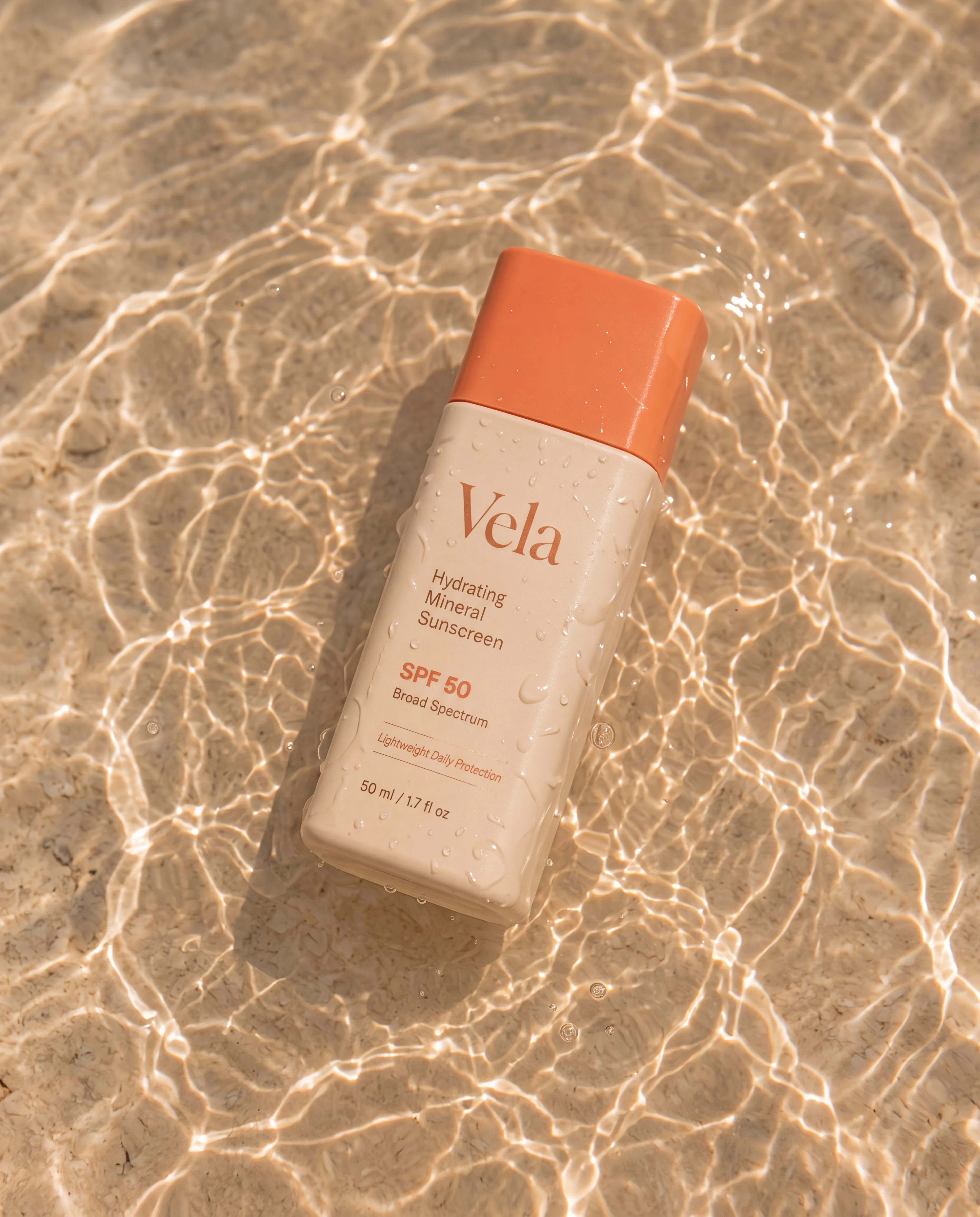 Vela sunscreen resting in clear shallow water with sunlit caustics