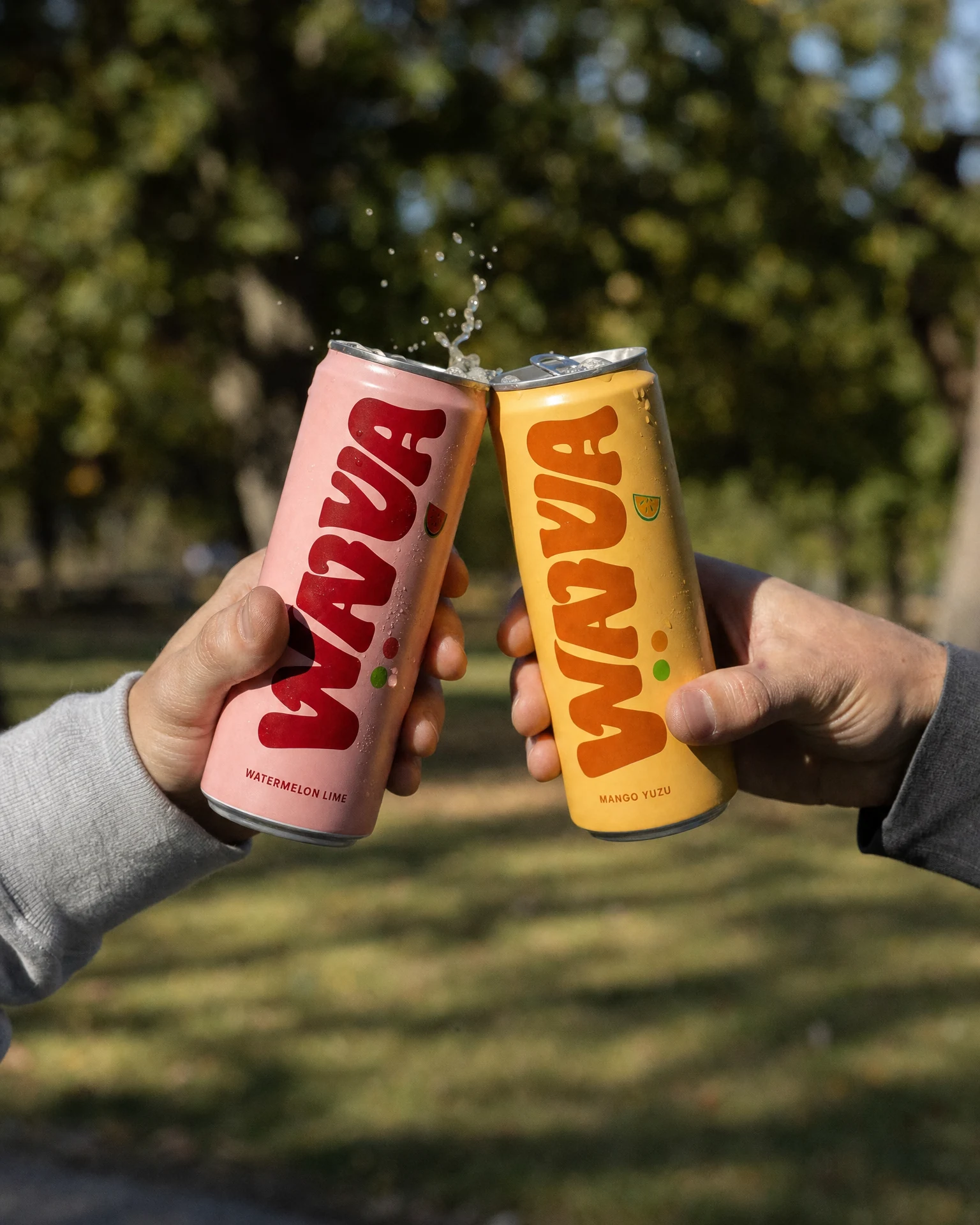 Two Wavva cans clinking in a high-speed beverage photograph