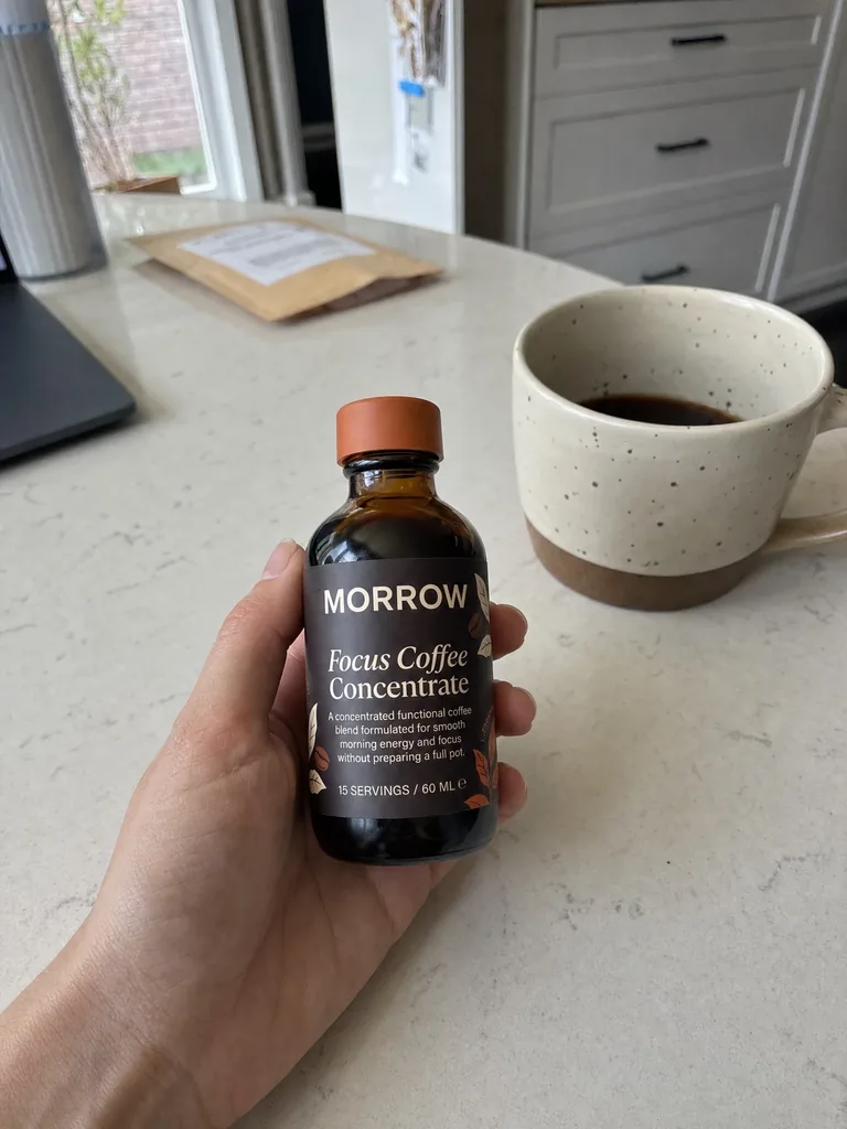Hand holding MORROW Focus Coffee Concentrate over a morning desk